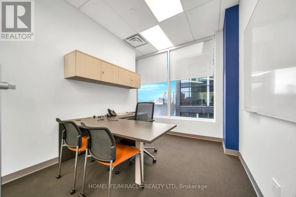 Small office with a desk, chairs, overhead cabinets, and a whiteboard overlooking the city. - 721 - 130 Queens Quay E, Toronto