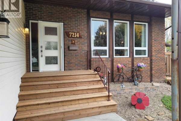 Wooden porch steps lead to the front entrance with a white door and brick exterior. - 7214 97 Street, Grande Prairie