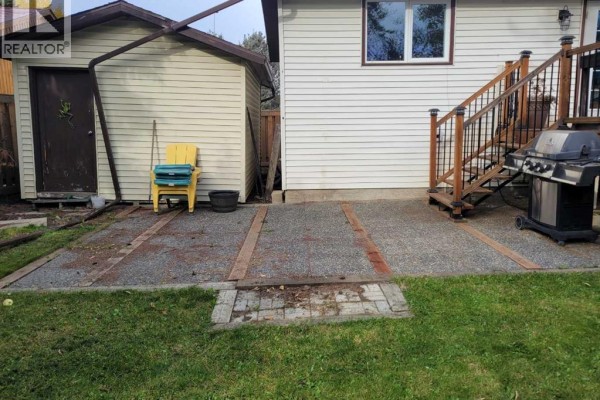 Backyard patio with gravel and brick border, next to a detached shed and outdoor grill. - 7214 97 Street, Grande Prairie