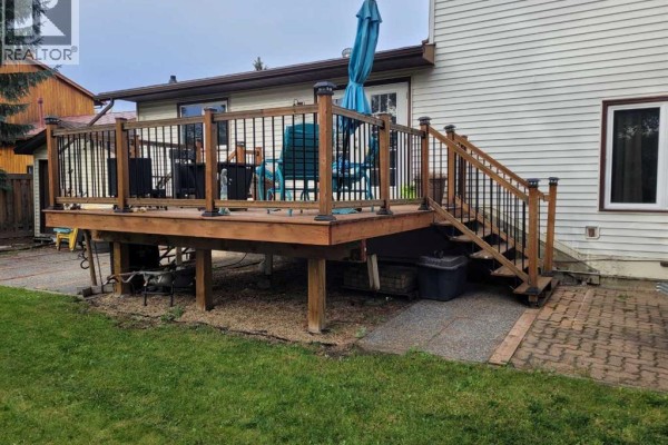 Raised wooden deck with black metal railings and solar lights, accessed by stairs. - 7214 97 Street, Grande Prairie