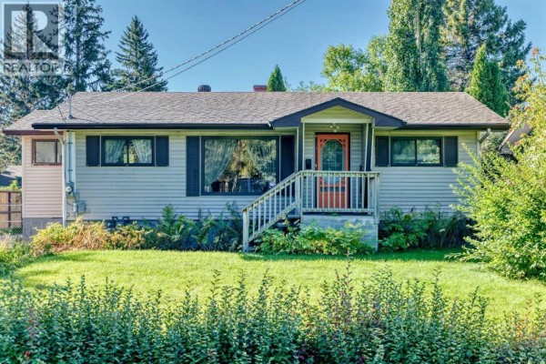Front exterior of a light beige siding bungalow with a porch and white railings. - 7219 Bow Crescent Nw, Calgary