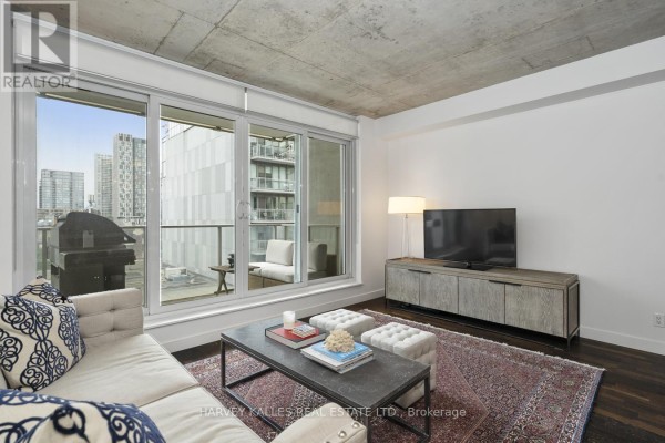 Living room with television on console and large window with balcony view. - 722 - 75 Portland Street, Toronto