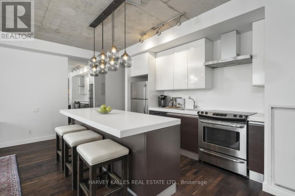 Modern kitchen with stainless steel appliances and white quartz island. - 722 - 75 Portland Street, Toronto