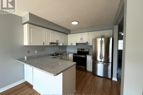 Kitchen with white cabinets, granite countertops, a stainless steel refrigerator, and a breakfast bar. - 722 Trailview Drive, Peterborough