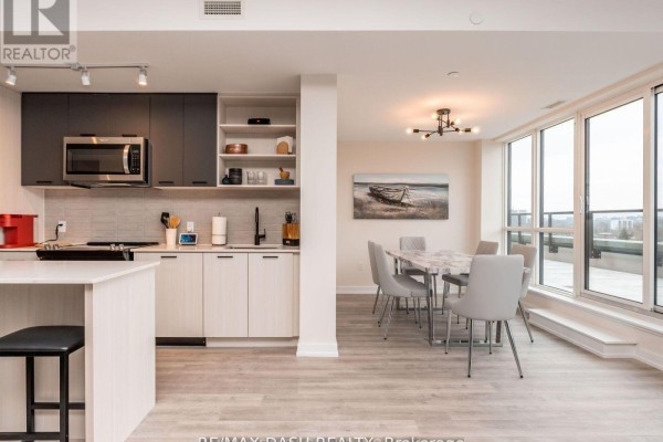 Kitchen with stainless steel appliances and grey and white cabinets, adjacent to a dining area with a table and chairs. - 723 - 2300 St. Clair Avenue W, Toronto