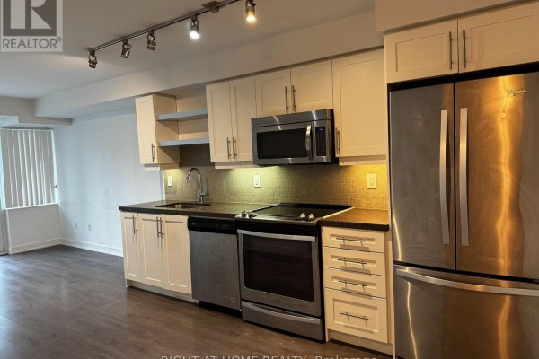 Kitchen view showing white cabinets, stainless steel appliances, dark countertop, and grey mosaic tile backsplash. - 723 - 525 Adelaide Street W, Toronto