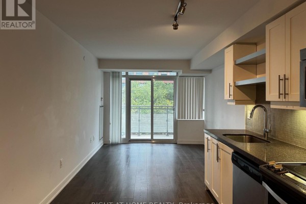 Living area with dark wood floors, white walls, and a sliding glass door leading to a balcony. - 723 - 525 Adelaide Street W, Toronto