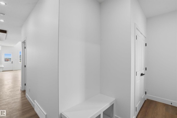 White hallway with a built-in white bench and doors leading to other rooms. - 723 158 Av Ne, Edmonton