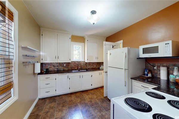 Kitchen with white cabinets, granite countertops, a white refrigerator and a white stove. - 723 9th Street E, Saskatoon