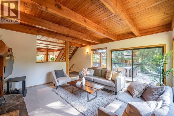 Dining room with a wooden table, chairs, a large bay window, and exposed wooden ceiling beams. - 7231 N Fitzsimmons Road, Whistler