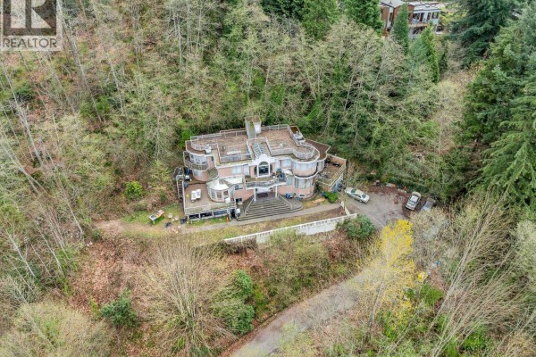 Aerial view of the main structure at 7235 Bayview Drive, surrounded by trees and a winding driveway. - 7235 Bayview Drive, Burnaby