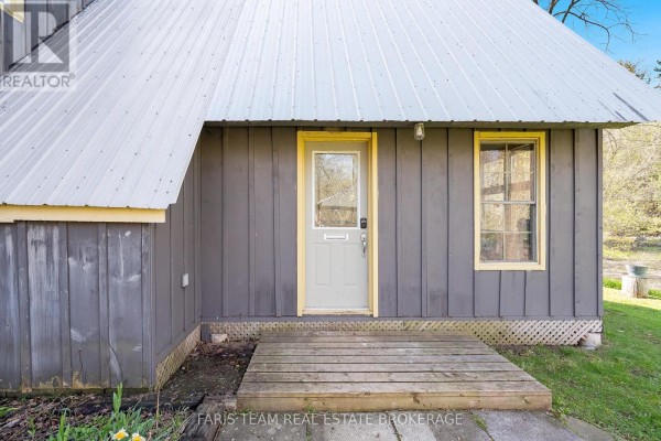 Close-up of the front door and window of a grey wood-sided house. - 7237 6/7 Sideroad Nottawasaga, Clearview