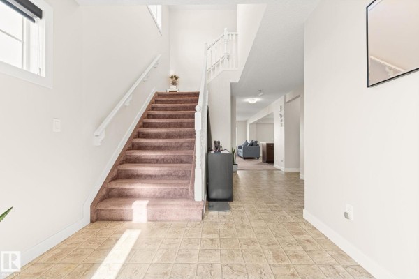 Large, empty bedroom with beige carpet and three windows with patterned curtains. - 724 40 Av Nw, Edmonton