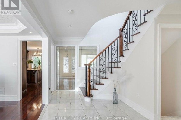 Interior foyer with tiled floor, hardwood flooring visible to the left, and a curved staircase. - 724 Peter Robertson Boulevard, Brampton