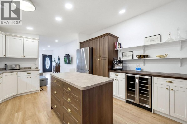 Kitchen with white cabinets, a dark wood island, stainless steel appliances, and a built-in wine fridge. - 7241 46 Street Ne, Salmon Arm
