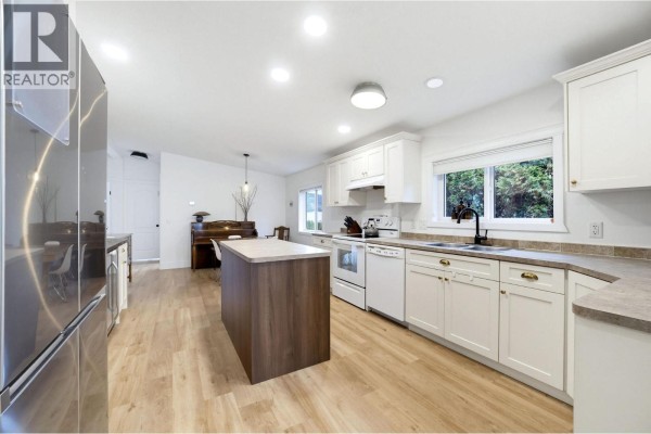 Kitchen with white cabinets, a wood island, stainless steel appliances, a sink, and a window view. - 7241 46 Street Ne, Salmon Arm