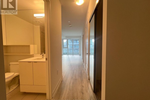 Hallway view showing a bathroom on the left and closet doors on the right, leading to a living area. - 725 - 60 Princess Street, Toronto