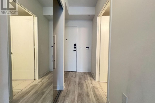 Apartment entrance hallway with white doors, a mirrored closet on the right, and light wood flooring. - 725 - 60 Princess Street, Toronto