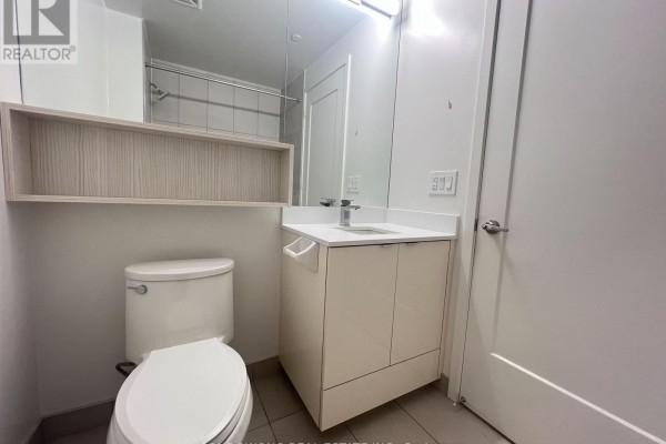 Bathroom with a white toilet, vanity with sink, and a large mirror above the vanity. - 725 - 60 Princess Street, Toronto