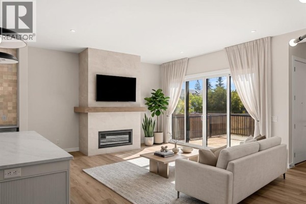 Living room with fireplace, television, neutral sofa, and large sliding glass doors to the deck. - 725 53 Avenue Sw, Calgary