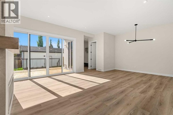 Spacious living area with blonde wood floors, fireplace, and sliding glass doors leading outdoors. - 725 53 Avenue Sw, Calgary