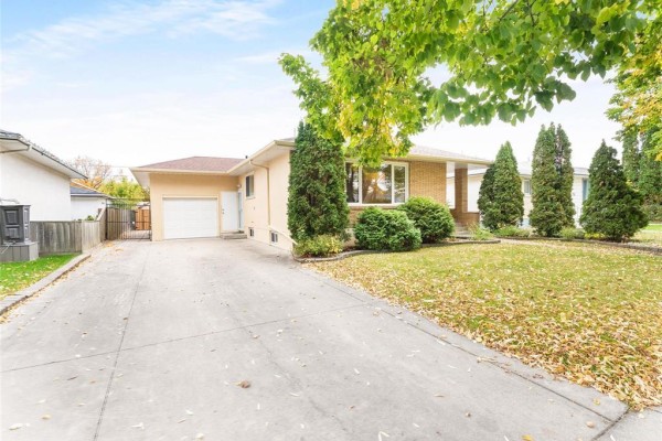 Side view of the house showing a detached garage and a long concrete driveway. - 725 Mcleod Avenue, Winnipeg