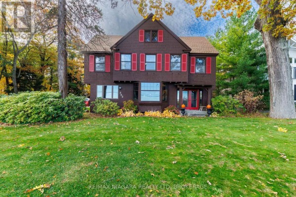 Front view of the house featuring brown siding, red shutters, and landscaped lawn. - 725 Point Abino Road S, Fort Erie
