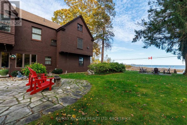 Side view of the house with red chairs, stone path, and lake view in the background. - 725 Point Abino Road S, Fort Erie