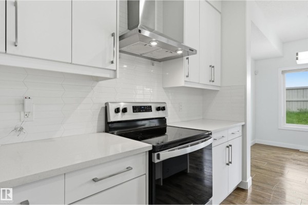 Close-up of a stainless steel range, white subway tile backsplash, and white cabinetry in the kitchen. - 7258 Chivers Pl Sw, Edmonton