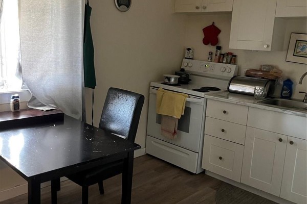 Small kitchen area with a dark wooden table, white cabinets, and a white stove. - 726 M Avenue S, Saskatoon