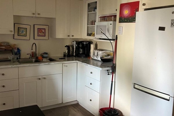 Corner view of a kitchen with white cabinets, marble countertops, and a white refrigerator. - 726 M Avenue S, Saskatoon