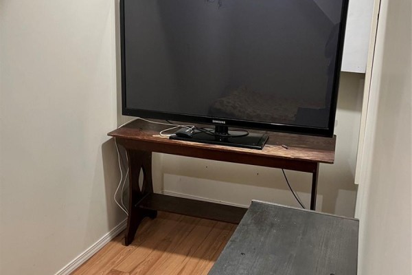 Television set on a dark wooden stand in a corner of a room. - 726 M Avenue S, Saskatoon