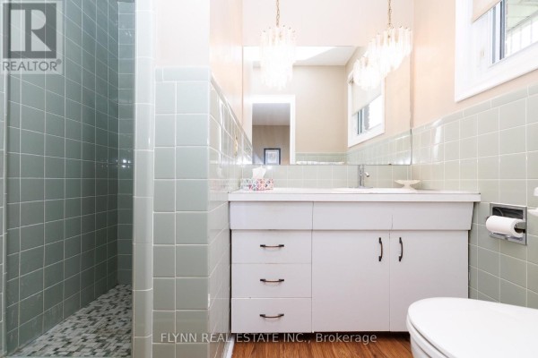 Mint green tiled bathroom with shower stall, vanity, and crystal chandelier - 7260 Mccoll Drive Niagara Falls