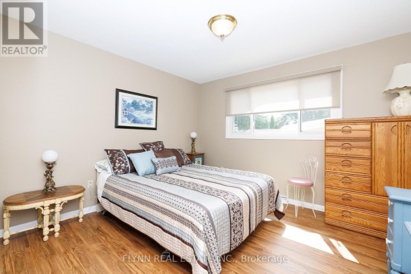 Bedroom with wood laminate floors, quilt, dresser, and chair - 7260 Mccoll Drive Niagara Falls