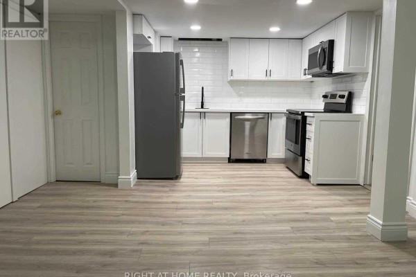A compact kitchen with white cabinetry, stainless steel appliances, and grey wood-look vinyl flooring. - 727 Down Crescent, Oshawa