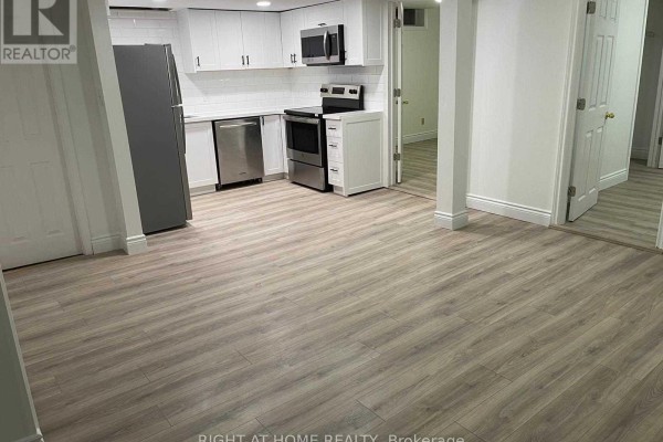 View of the kitchen and adjacent room with light grey wood-look vinyl flooring. - 727 Down Crescent, Oshawa