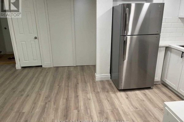 Side view of a stainless steel refrigerator and white kitchen cabinets with grey flooring. - 727 Down Crescent, Oshawa