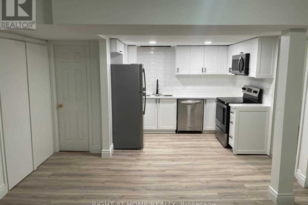 Wide view of a modern basement kitchen with white cabinets, stainless appliances, and grey flooring. - 727 Down Crescent, Oshawa