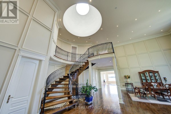 Circular foyer with a dramatic spiral staircase, black metal railings, and a central skylight. - 727 Sunset Beach Road, Richmond Hill
