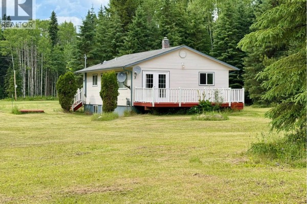 A narrow dirt path winds through a dense forest with tall evergreen trees and green undergrowth. - 7280 Otway Road, Prince George