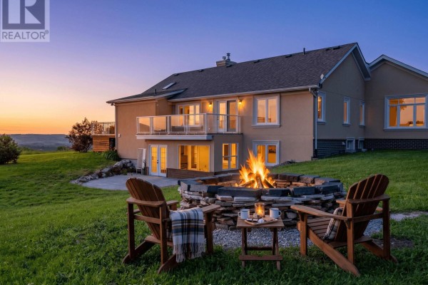 Stone fire pit with two Adirondack chairs in front of a house at dusk. - 728454 21st Side Road, Blue Mountains
