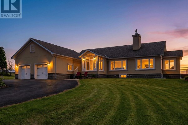 Exterior of a long, single-story tan house with a three-car garage at dusk. - 728454 21st Side Road, Blue Mountains
