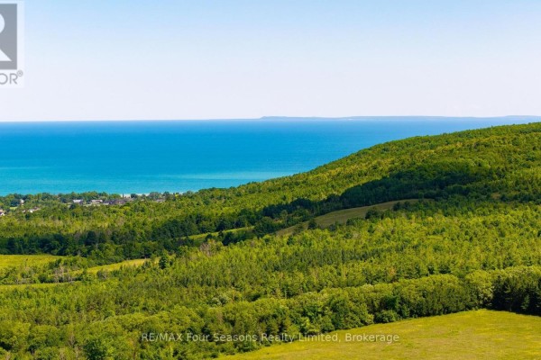 View of Georgian Bay over a green, tree-covered hillside. - 728454 21st Side Road, Blue Mountains