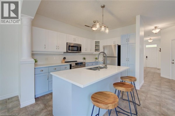 Kitchen with white cabinets, blue lower cabinets, an island with pendant lights, and stainless steel appliances. - 729 Keats Way, Waterloo