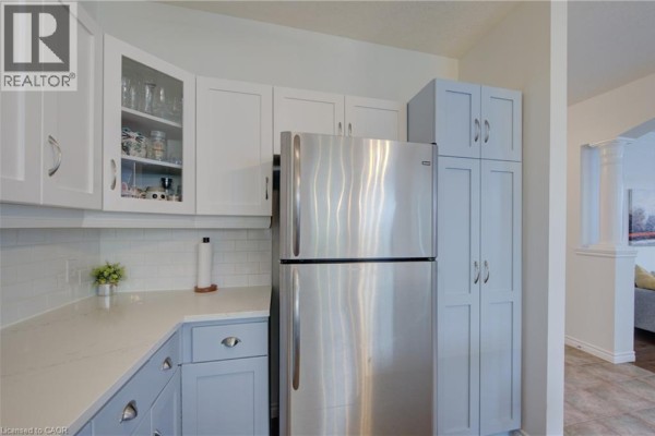 Kitchen with a central island and light blue lower cabinets, looking down a hallway with interior doors. - 729 Keats Way, Waterloo