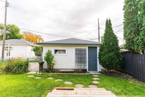 Rear view of a detached garage with a dark grey door, a small window, and a stepped pathway. - 729 Kildonan Drive, Winnipeg