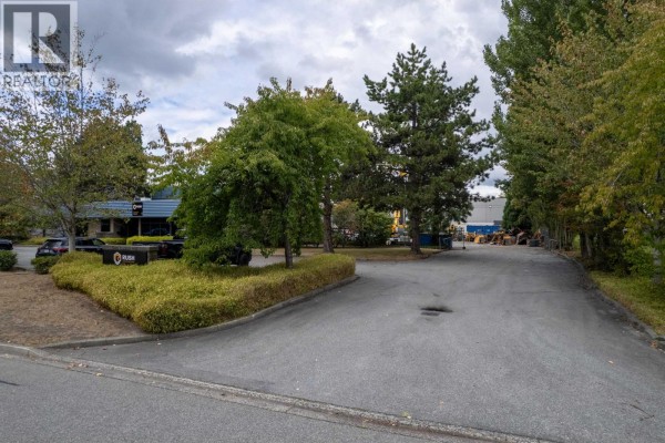 View of the paved driveway leading to the commercial building, surrounded by trees and greenery. - 7293 Wilson Avenue, Delta