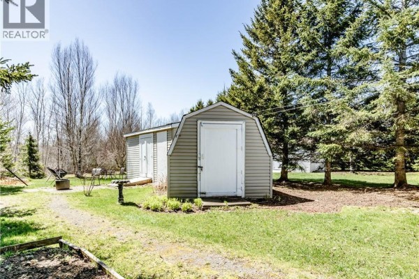 Open concept kitchen and dining area with wood cabinets, white appliances, and a wooden table with chairs. - 73 Andre, Dieppe