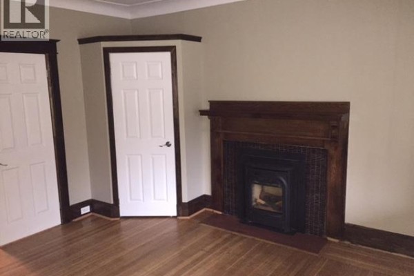 Living room with hardwood floors, white doors, dark wood trim, and a dark tile fireplace. - 73 Barnesdale Boulevard Unit# 1, Hamilton