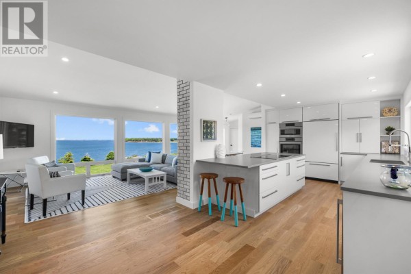 Open concept kitchen with white cabinets and island, adjacent to a living room with water view. - 73 Four Winds Lane, Stanley Bridge, Stanley Bridge